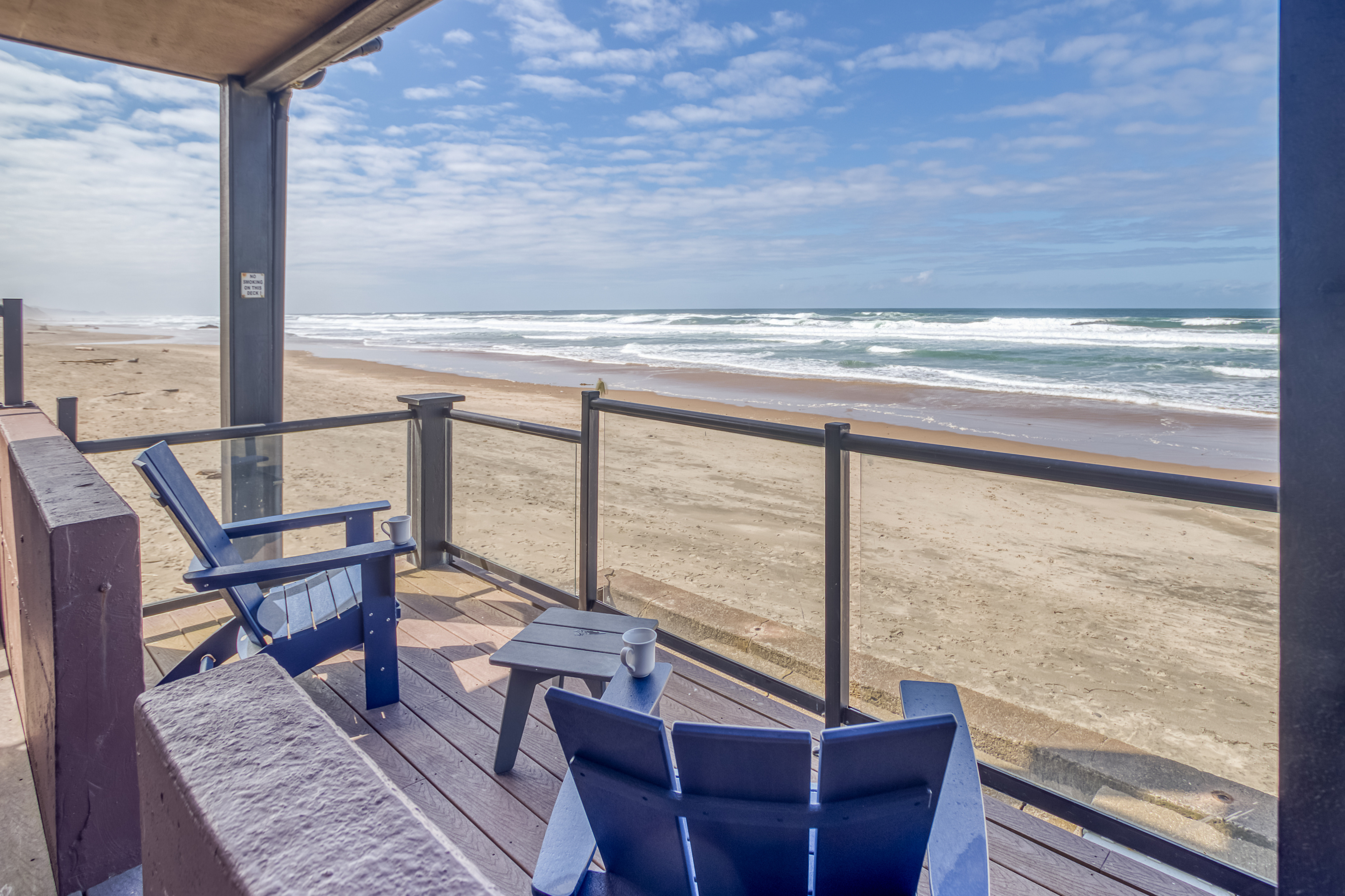 a deck with chairs and a table on the beach